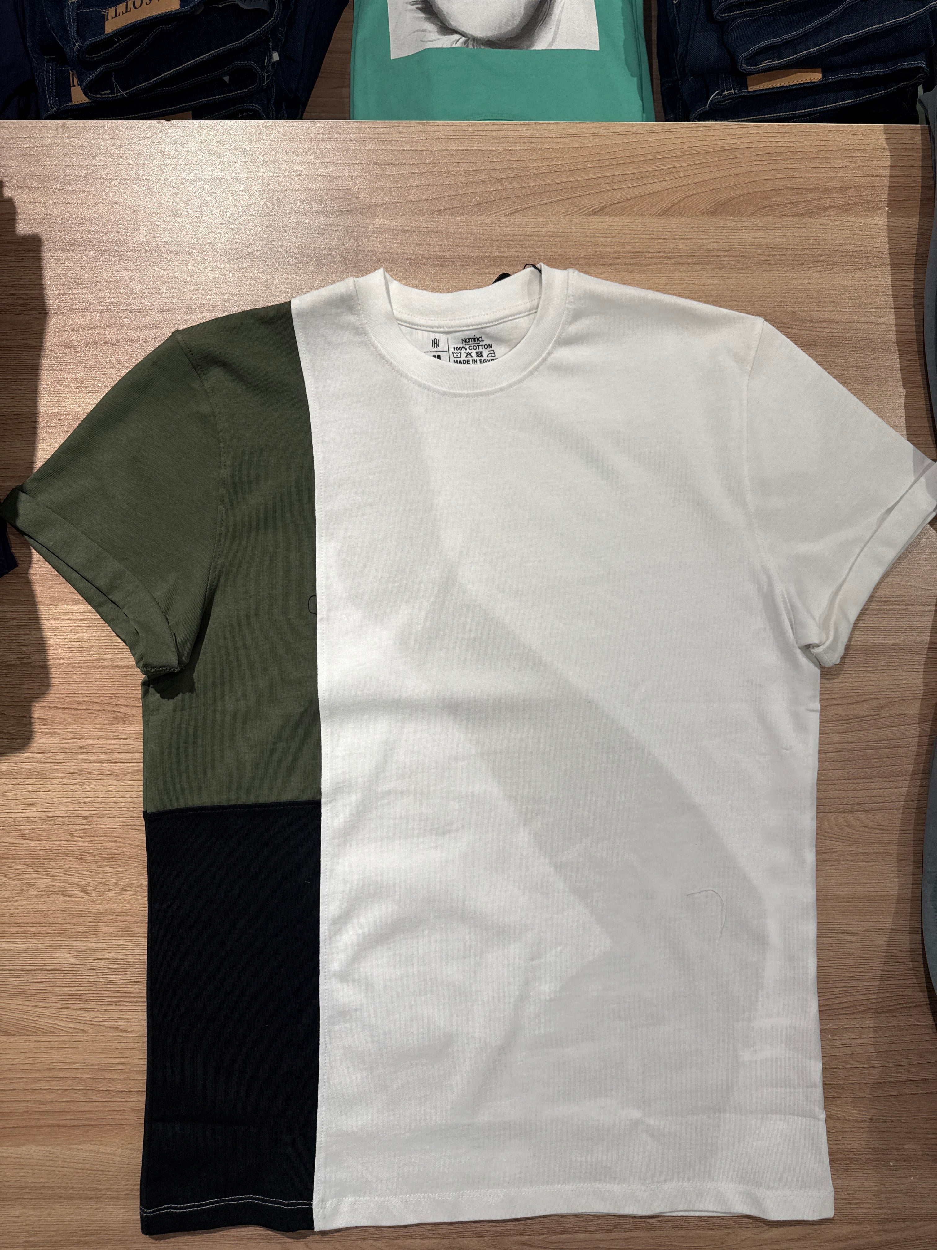 White t-shirt with black and green design on a wooden surface