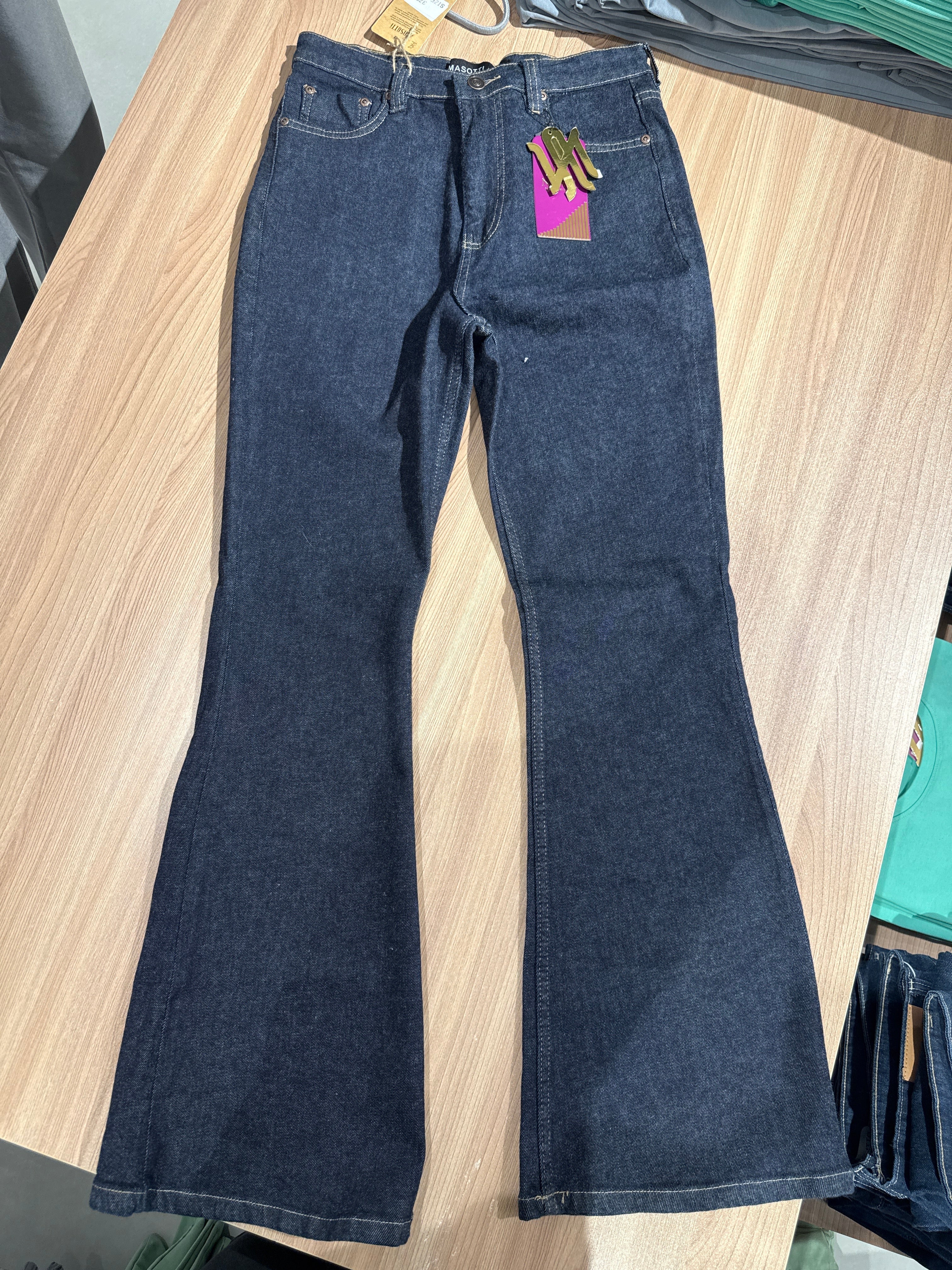 Folded dark blue jeans on a wooden surface with a visible brand tag.